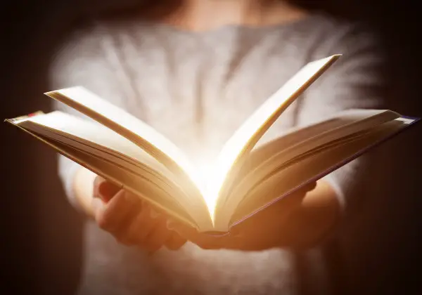 Light coming from book in woman's hands in gesture of giving