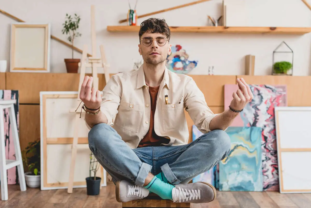 Dreamy artist with closed eyes sitting in lotus pose